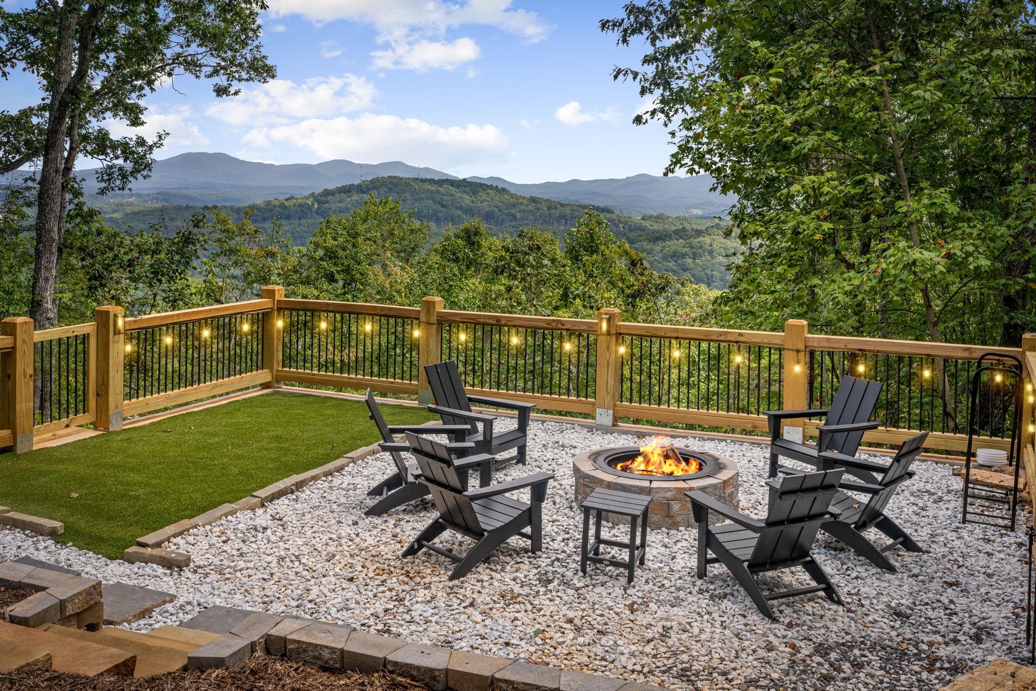 Outdoor stone bonfire pit burning with Adirondack chairs and mountain views at Blue Ridge Georgia luxury cabin rental