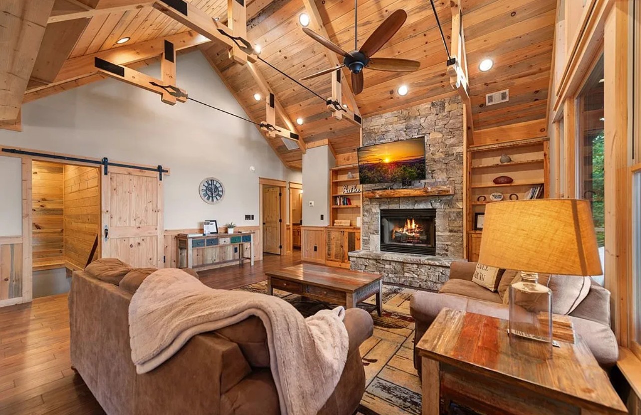 Eversky on Sunrock living room with vaulted wood ceiling, stone fireplace, and cozy furnishings
