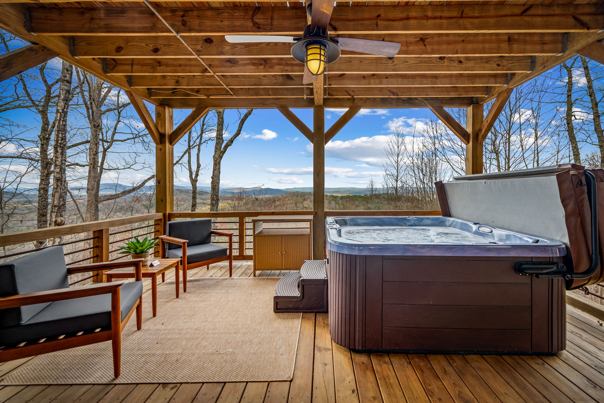 Covered pergola deck with hot tub and lounge seating overlooking the Blue Ridge Mountains at Blue Ridge Georgia cabin rental